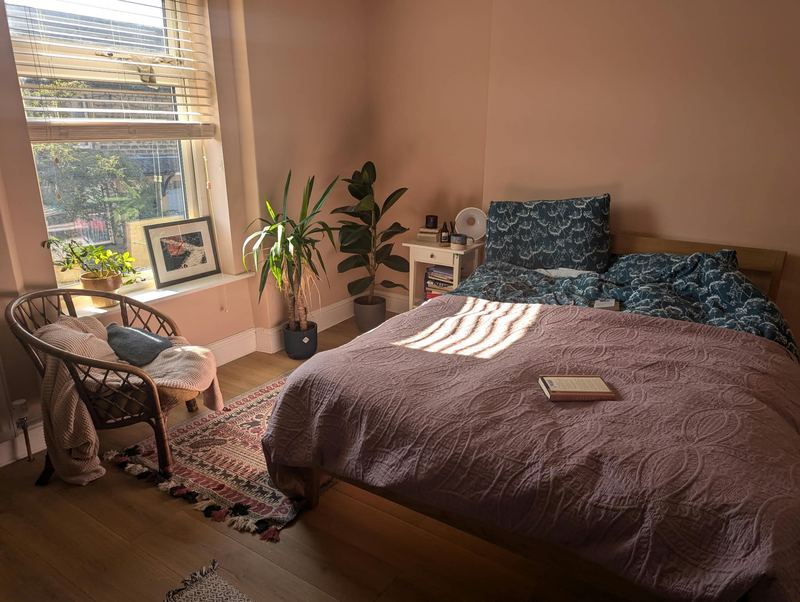 Bedroom 1, a double room with a large window, blush-pink walls and a wooden floor