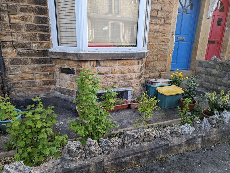 Front yard with planted borders and a stone bay window