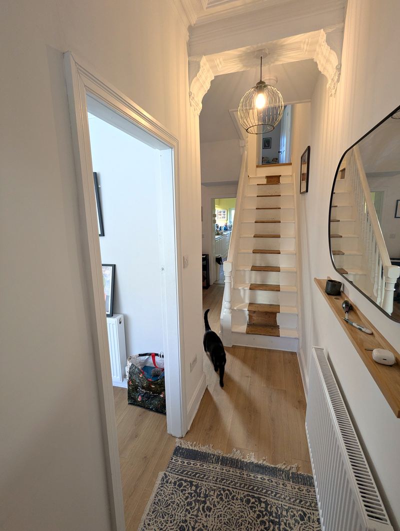 Hallway with a wooden floor and runner rug leading to the staircase