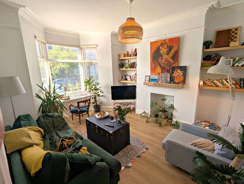 Lounge with a bay window, alcove shelving, a fireplace and a wooden floor