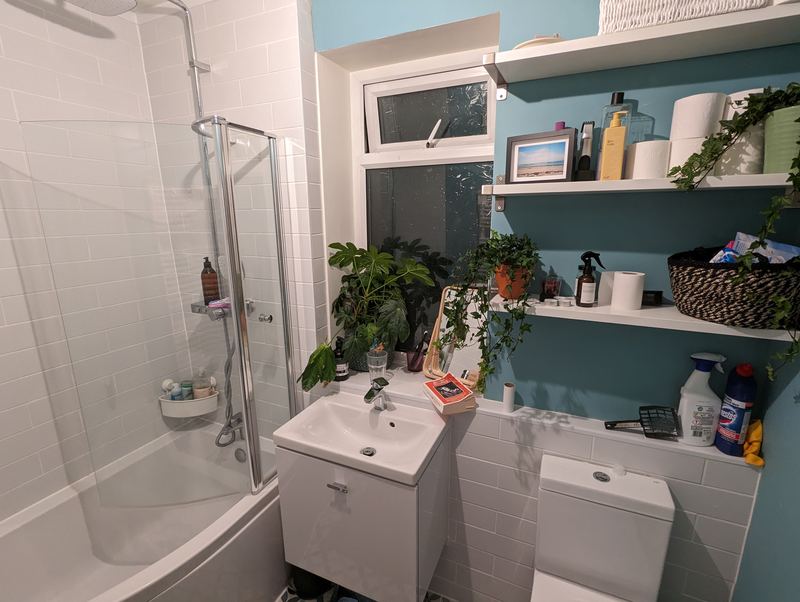 Tiled bathroom with a bath, glass screen and basin